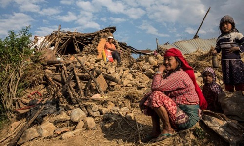 Thủ tướng Nepal: '10.000 người có thể thiệt mạng vì động đất' Người dân ngồi trước ngôi nhà bị động đất phá hủy ở Kathmandu. Ảnh: EPA