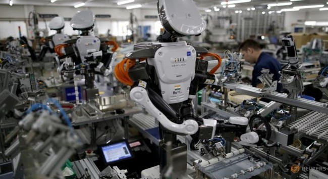 Công ty Nhật đầu tư mua robot thay nhân lực Robot cùng làm việc với nhân viên trong dân chuyền lắp ráp tại một nhà máy của công ty Glory ở phía bắc Tokyo - Ảnh: Reuters