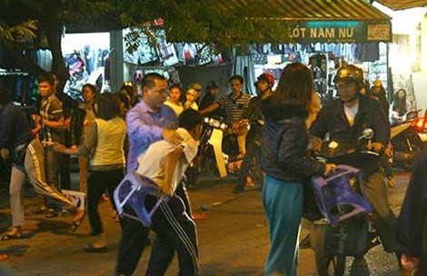 Lo Một người đàn ông cầm ghế nhựa đuổi theo đánh một khách hàng vì đi vào vỉa hè, vướng đồ của quán ông ấy bày ra và được người đi đường can ngăn.