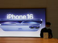 Một người đàn ông ngồi cạnh quảng cáo iPhone 16 tại một cửa hàng Apple ở Bắc Kinh (Ảnh: SCMP)