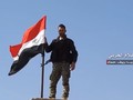 Một binh sĩ Syria thượng cờ trên thị trấn vừa giải phóng. Video truyền thông Hezboaah