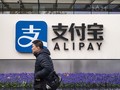 Một người đi qua chi nhánh Alipay ở Thượng Hải, Trung Quốc (ảnh: Bloomberg)