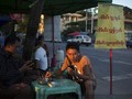 Sóng Viettel sắp chính thức phủ lên đất Myanmar. Trong ảnh là một người đàn ông Myanmar sử dụng điện thoại di động khi đang ngồi quán vỉa hè ở Yangon - Ảnh: Bloomberg.