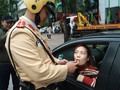 Người phụ nữ lái ô tô vui vẻ thổi kiểm tra nồng độ cồn. Ảnh: Hiệp Bình.