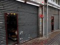 Chủ một cửa hiệu quan sát cuộc biểu tình qua cánh cửa đóng kín tại Sheung Shui (Ảnh: Reuters)