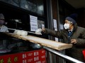 Lo sợ virus corona, người bán hàng ở Bắc Kinh không dám trực tiếp nhận tiền của khách mua (Ảnh: Reuters)