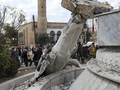 Người dân đứng gần bức tượng cố Tổng thống Syria Hafez al-Assad bị hư hại sau khi phe nổi dậy Syria tuyên bố đã lật đổ Tổng thống Bashar al-Assad, ở Qamishli, Syria. Ảnh: Reuters.