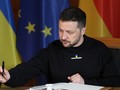 Tổng thống Ukraine Volodymyr Zelensky đang ký vào một cuốn sổ lưu bút. Ảnh: Getty.