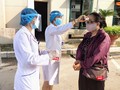 Nhân viên y tế đo thận nhiệt cho người dân đến khám bệnh. Ảnh: Minh Thúy