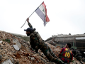Một binh sĩ trong quân đội của chính phủ Syria cắm lá cờ quốc gia trong một trận chiến với các nhóm phiến quân tại tiền tuyến Ramouseh nằm tại phía đông thành phố Aleppo vào ngày 5.12.2016.