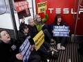 Người biểu tình chống Elon Musk vào ngồi lỳ trong cửa hàng Tesla cản trở hoạt động kinh doanh. Ảnh: QQnews.
