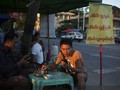 Sóng Viettel sắp chính thức phủ lên đất Myanmar. Trong ảnh là một người đàn ông Myanmar sử dụng điện thoại di động khi đang ngồi quán vỉa hè ở Yangon - Ảnh: Bloomberg.