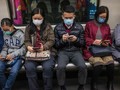 Người dùng smartphone đeo khẩu trang trên một chuyến tàu ở Hong Kong. Ảnh: AFP.