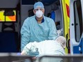Nhân viên NHS chuyển bệnh nhân COVID-19 từ xe cứu thương (Ảnh: Reuters)