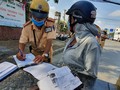 Một người phụ nữ bị CSGT phạt vì mang giấy tờ xe photo dù có chứng thực. Ảnh: Thanh Niên