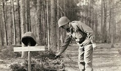 Một lính Mỹ đặt các cành thông lên mộ của lính Mỹ vô danh, bị quân Đức chôn trước khi rút lui.