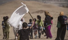 Một em nhỏ cầm cờ trắng trong dòng người chạy thoát khỏi Mosul