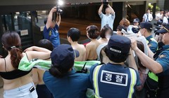 Ngay khi các phóng viên xuất hiện, những người phụ nữ đã cởi áo ngoài để truyền tải thông điệp: "Cơ thể chúng tôi không phải tài liệu khiêu dâm" (ảnh: Yonhap)