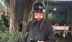 Một người ăn xin mặc đồ đen, mặt biến dạng bị người dân chụp ảnh.