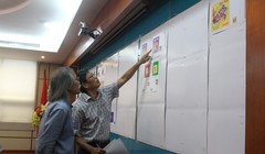 Các thành viên Hội đồng chấm thi xem xét, đánh giá và lựa chọn các mẫu tem Tết. Ảnh: MIC.gov.vn