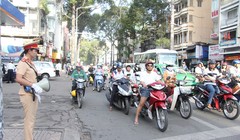 Nữ cảnh sát giao thông phát loa tuyên truyền tại giao lộ. Ảnh: Cổng thông tin điện tử của Bộ Giao thông Vận tải.