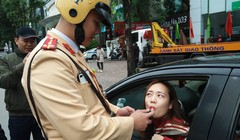 Người phụ nữ lái ô tô vui vẻ thổi kiểm tra nồng độ cồn. Ảnh: Hiệp Bình.