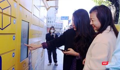 Người dân Hà Nội trải nghiệm trạm giao nhận thông minh bằng thao tác trên điện thoại và màn hình cảm ứng tại trạm.
