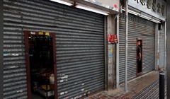 Chủ một cửa hiệu quan sát cuộc biểu tình qua cánh cửa đóng kín tại Sheung Shui (Ảnh: Reuters)