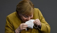 Bà Merkel nhịn cười khi đang đeo lại khẩu trang của mình (Ảnh: Getty)