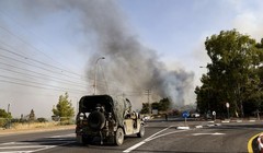 Một chiếc xe jeep của quân đội Israel đậu gần trạm kiểm soát khi khói bốc lên từ đám cháy do tên lửa phóng từ miền nam Lebanon, ở Thượng Galilee, Israel ngày 4/7/2024 (Ảnh: AFP)