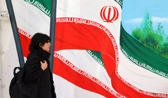 Một người phụ nữ đi ngang qua bức tranh tường vẽ cờ Iran ở Tehran. Truyền hình nhà nước Iran đã cố nói giảm về tác động của đòn tấn công của Israel (Ảnh: AFP)