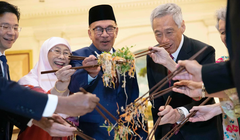 Các chính trị gia, bao gồm Thủ tướng đương nhiệm Singapore Lawrence Wong (trái) và Thủ tướng Malaysia Anwar Ibrahim (thứ ba từ trái sang), trộn một đĩa Yusheng trong lễ đón Tết Nguyên đán năm 2023. Ảnh: AFP.