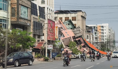 Người dân đi xe máy qua một tòa nhà bị đổ sập sau trận động đất ở Mandalay, Myanmar hôm 28/3. Ảnh: Reuters.