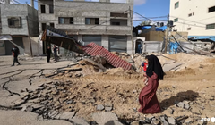 Một người phụ nữ đi bộ qua một con đường bị phá hủy sau cuộc không kích của Israel tại Khan Younis ở phía nam Dải Gaza vào ngày 14/5. Ảnh: AFP.