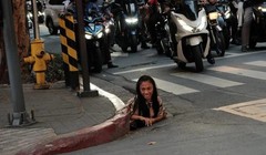 Một người phụ nữ được chụp ảnh đang chui ra khỏi một lỗ thoát nước dọc theo một con phố ở thành phố Makati, Philippines. Ảnh: William Roberts.