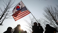 Một người cầm cờ Hàn Quốc và cờ Mỹ ở Uiwang, Hàn Quốc vào ngày 8/3. Ảnh: Reuters.