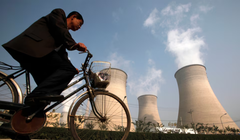 Một người đàn ông đạp xe qua ống khói của một nhà máy điện nằm ở ngoại ô Bắc Kinh vào ngày 29/10/2009. Ảnh: Reuters.