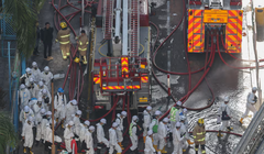 Cảnh sát mặc đồ bảo hộ đi bộ gần hiện trường vụ cháy chung cư tại khu nhà ở Wang Fuk Court sau vụ hỏa hoạn chết người ở Tai Po, Hong Kong, Trung Quốc, ngày 29/11. Ảnh: Reuters.