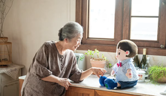 Một phụ nữ lớn tuổi tương tác với chú robot nhồi bông Hyodol được hỗ trợ bởi AI. Ảnh: Hyodol.