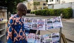 Một người bán hàng đang xem những tờ báo được trưng bày trên một gian hàng ở Cotonou, vào ngày 8/12. Ảnh: AFP.