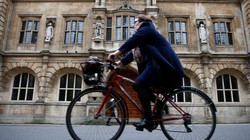 Một người phụ nữ đi xe đạp bên cạnh trường Oriel College ở Oxford, Anh (ảnh: Thomson Reuters)