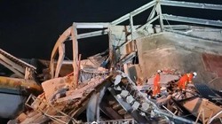 Các nhân viên cứu hộ tìm kiếm nạn nhân trong đống đổ nát (Ảnh: Nhân dân Nhật báo).