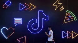 Một người đàn ông cầm điện thoại đi ngang qua biển hiệu có logo ứng dụng Douyin của ByteDance tại Hàng Châu, tỉnh Chiết Giang, Trung Quốc. (Ảnh:SCMP)