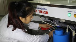 TS Nguyễn Thị Thanh Hải - đồng tác giả Giải pháp hữu ích - bên một thiết bị sản xuất anolit thường dùng trong bệnh viện, trạm y tế, trường học. Ảnh: Phạm Phượng