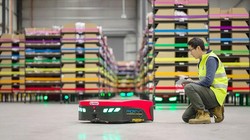 Một nhân viên của Mushiny kiểm tra một robot di động tự động tại một nhà kho ở Australia. Ảnh China Daily.