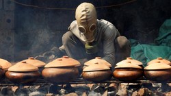 Anh Bùi Văn Cường đeo mặt nạ phòng độc để kho cá trắm (ảnh: Reuters)