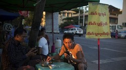 Sóng Viettel sắp chính thức phủ lên đất Myanmar. Trong ảnh là một người đàn ông Myanmar sử dụng điện thoại di động khi đang ngồi quán vỉa hè ở Yangon - Ảnh: Bloomberg.