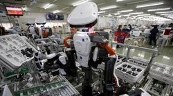 Robot làm việc cạnh con người trong dây chuyền lắp ráp tại một nhà máy của Glory, miền Bắc Tokyo (Nhật Bản) hôm 1/7/2015. Ảnh: Reuters