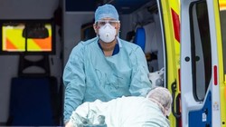 Nhân viên NHS chuyển bệnh nhân COVID-19 từ xe cứu thương (Ảnh: Reuters)