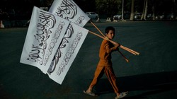 Một cậu bé bán cờ Taliban trên đường phố Kabul, Afghanistan (Ảnh: France24)